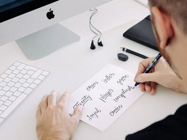 Person writing calligraphy at computer desk