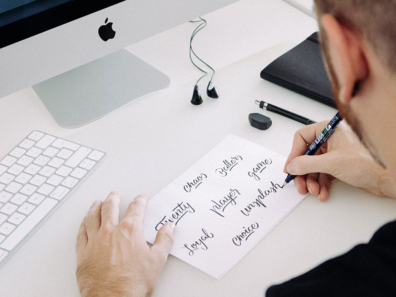 Person writing calligraphy at computer desk