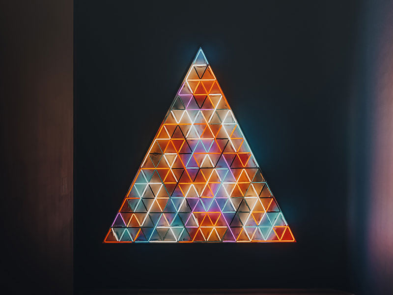 Colorful illuminated triangular mosaic pyramid on wall