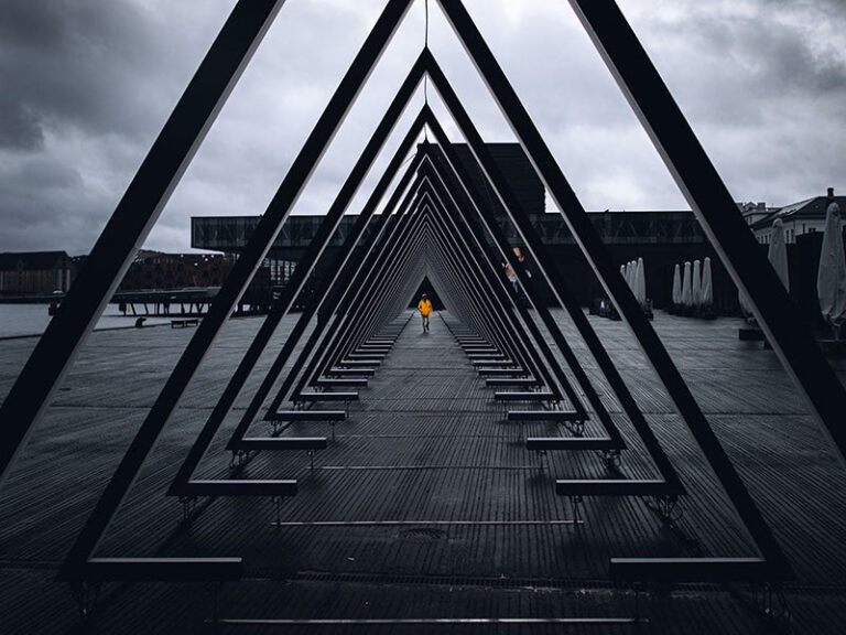Person in orange coat walking through metal triangles