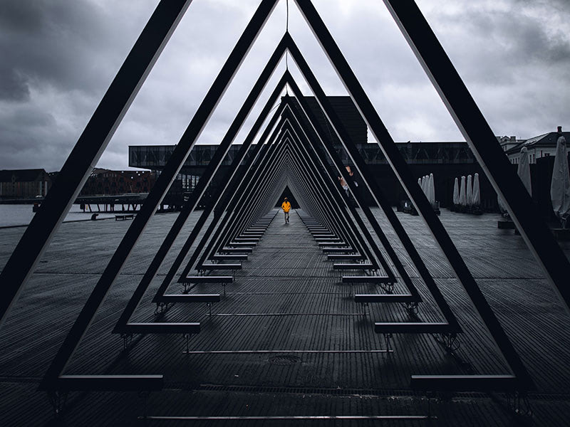 Person in orange coat walking through metal triangles